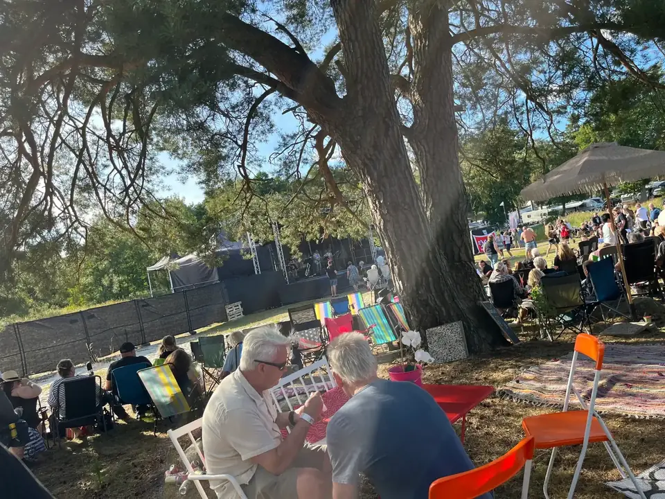 Äldre par samtalar vid festivalscen i kvällssol
