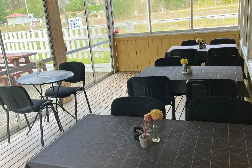 Inglasad servering med svarta bord och blommor